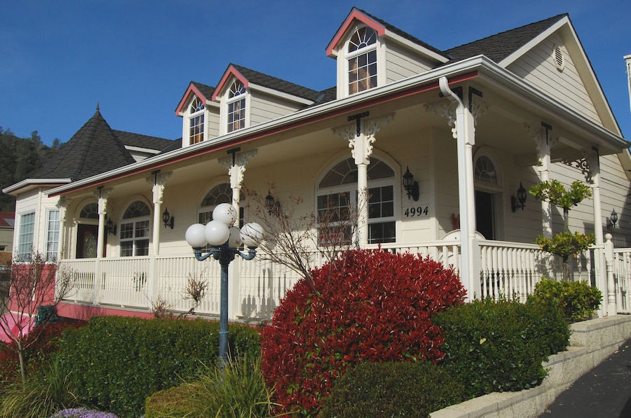 A two-story house with a porch, arched windows, and a chimney. - 5th Street Inn (Mariposa)