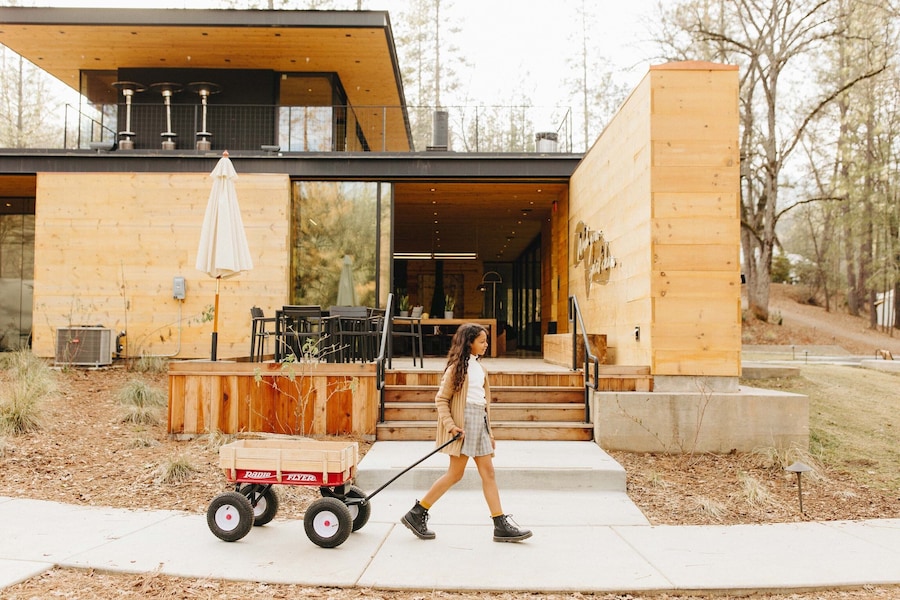 A modern wooden house with a large glass door, a wooden deck, and a small cart. - AutoCamp Yosemite (Mariposa)