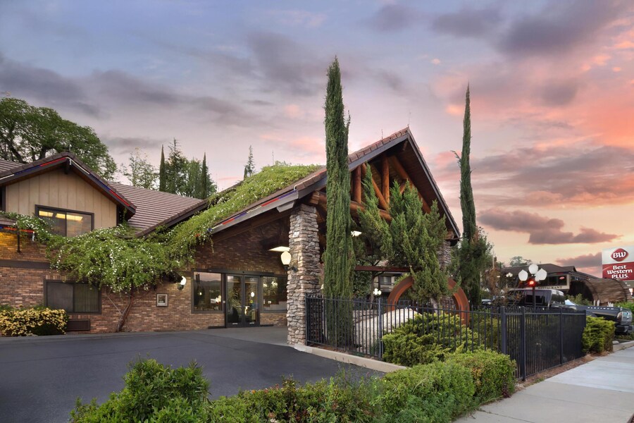 A hotel with a stone facade, large windows, and a covered entrance. - Best Western Plus Yosemite Gateway Inn (Oakhurst)